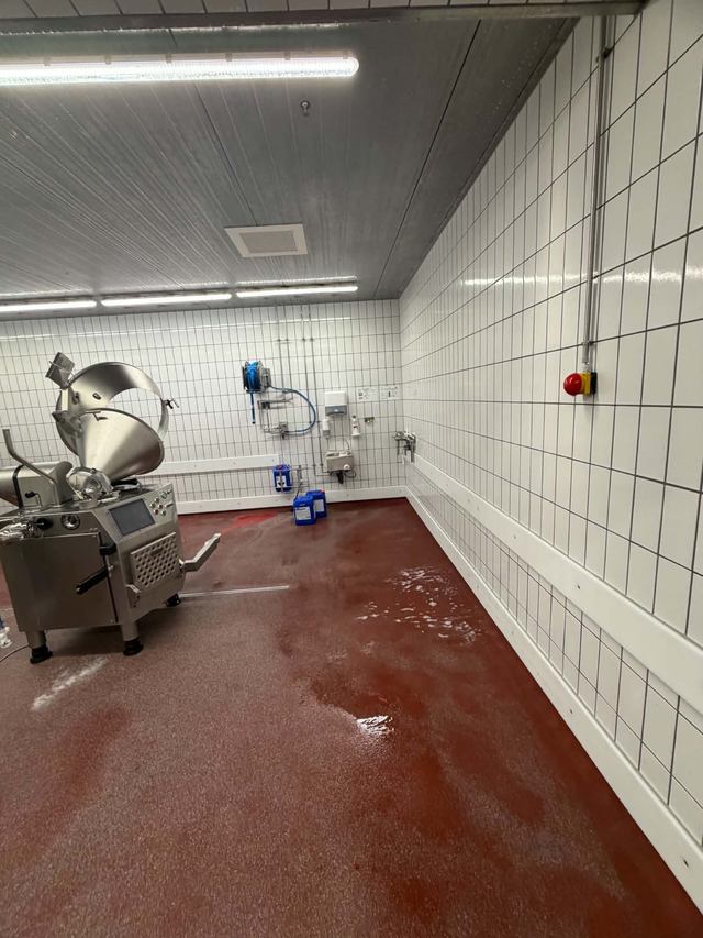 Roter Boden und weiße Wandfliesen im Produktionsbereich während der Reinigung