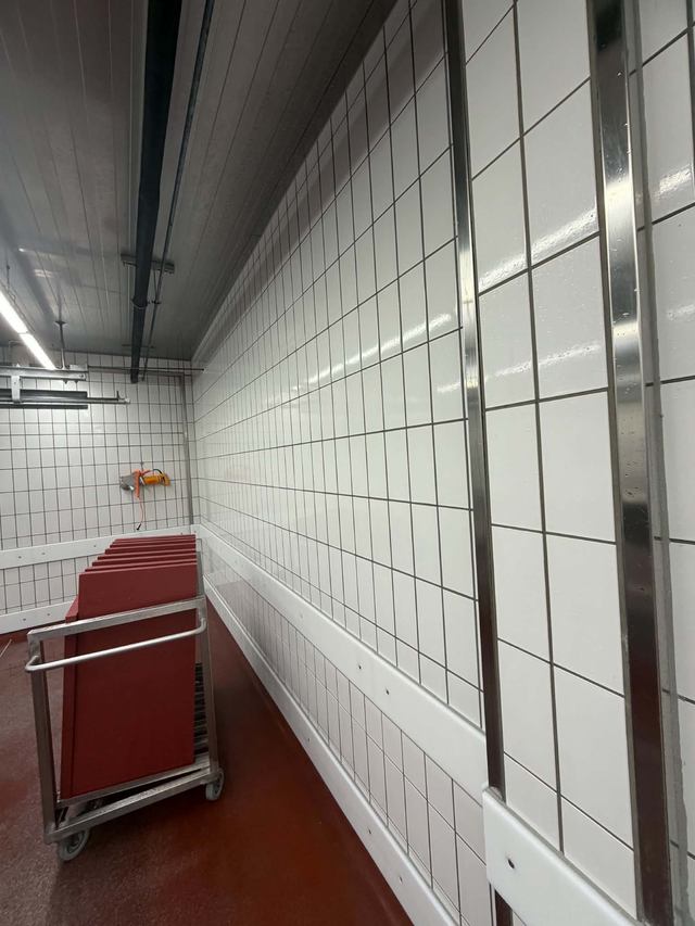 Geflieste Wand, roter Industrieboden und Transportwagen mit roten Platten
